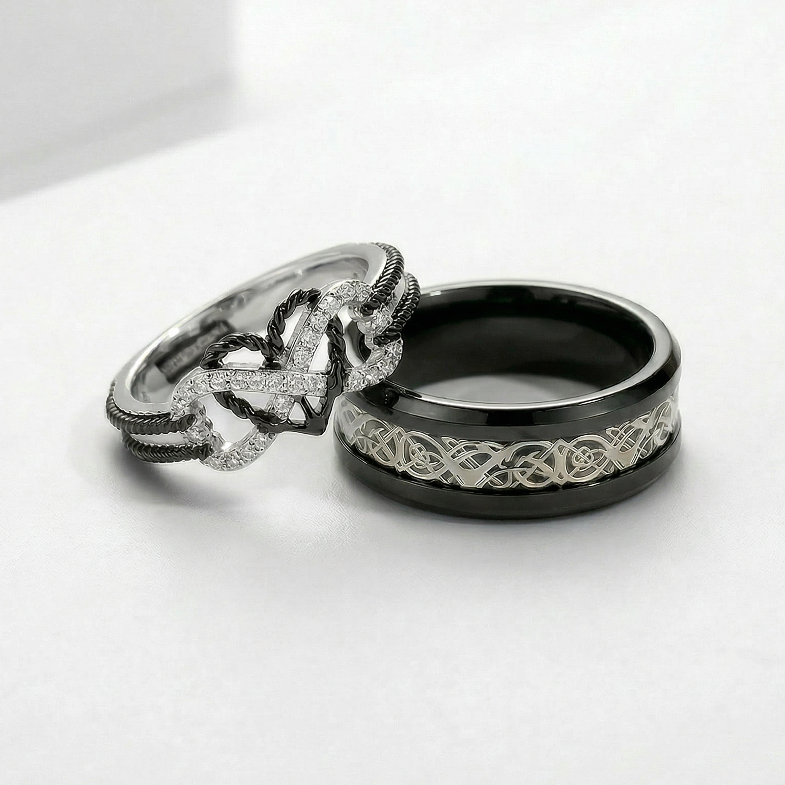 Two rings with intricate designs on a white surface